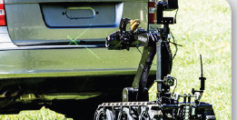 Lance Disrupter on an ICOR tracked robot with the Zero Convergence lasers active, placing an under-vehicle shot at the rear of an SUV