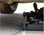 Scabbard Stand deployed under a vehicle, the disrupter aimed from beneath the wheel arch on its low profile